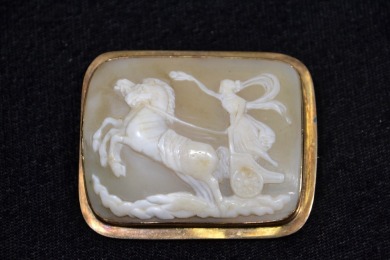 Jewellery - Brooch featuring a Sardonyx cameo depicting a winged lady driving a two horse chariot. Framed in Gold, Tested 12kt.